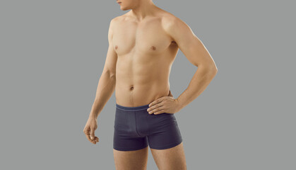 Fototapeta na wymiar Crop of toned sexy man in underwear isolated on grey studio background advertise garment. Sporty fit guy in briefs advertisement of underclothing wear. Fashion and style. Narrow banner.