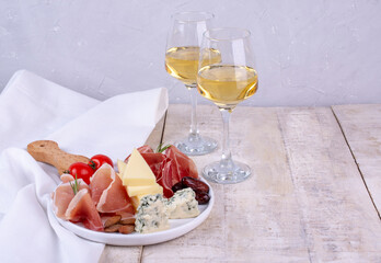Traditional Italian appetizers or antipasto. Salami, bresaola, prosciutto and cheese. Glass of white wine. Copy space	