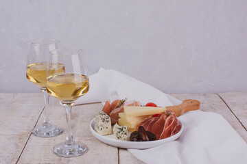 Traditional Italian appetizers or antipasto. Salami, bresaola, prosciutto and cheese. Glass of white wine. Copy space	
