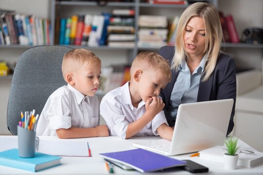 Woman teacher with childs using laptop in class at school.