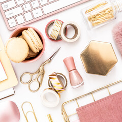 A femininely styled desktop in shades in gold and dusty pink with modem stationery. Lifestyle theme inspired by the office workspace of a stylish woman. Flat lay with fresh flowers pink keyboard and