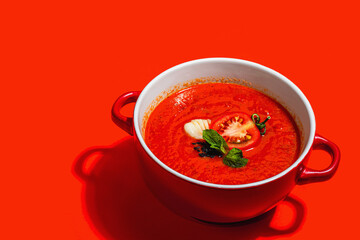 Spicy tomato soup. Healthy vegan hot dish, croutons, vintage cutlery. Bright red background