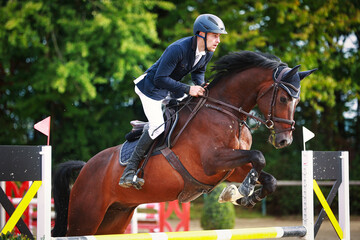 Show jumper closeup with horse over the obstacle during a tournament..