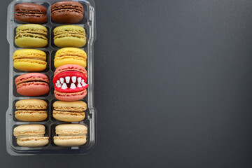  Fun macaroons with plastic teeth. Multicolored macaroons in clear packaging on a gray background