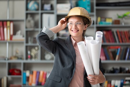 Female architect with blueprint in helmet on office background