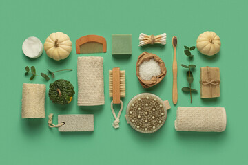 Fototapeta na wymiar Accessories for body care made of natural materials on a green background. Natural soap with cotton pads and wooden brushes.