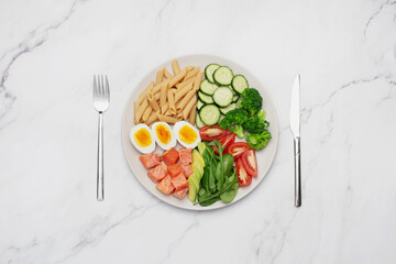 Fish with pasta, egg and avocado in a gray plate on a gray background. Healthy food. Recipe. Lunch...