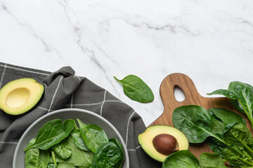 Gray culinary background with ingredients for green salad. Spinach with avocado and grapes.