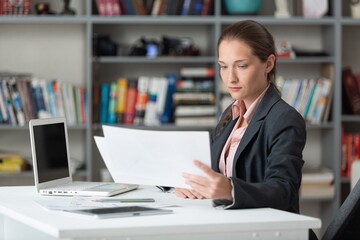 Young business woman working with paper documents, in office.