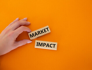 Market impact. Concept word Market impact on wooden cubes. Beautiful orange background. Businessman hand. Business and Market impact concept. Copy space.
