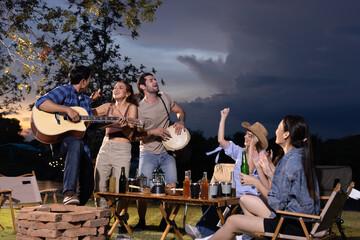 Happy diverse group of friends together playing guitar and sing enjoying with dancing in camping gardenview at night, Enjoy holiday vacation trip concept
