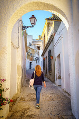 Fototapeta na wymiar Woman walking down a narrow street in a village with white houses in Andalucia, Cadiz.