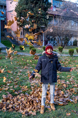 Boy throwing leaves up in autumn in Tbilisi Georgia