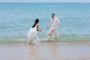 Fototapeta na wymiar Happy wedding couple running by the beach. Romantic feelings and vibes.