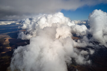Aerial view from airplane window at high altitude of earth covered with puffy cumulus clouds...
