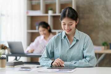 Fototapeta premium Beautiful young Asian business woman using tablet to work smiling and enjoying her job.