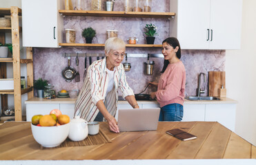 Elderly multiethnic friends cooking food according to recipe from internet