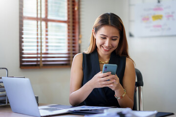 Happy Asian businesswoman working with a smile and using her smartphone for business communication...