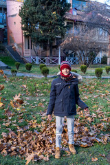 Boy throwing leaves up in autumn in Tbilisi Georgia