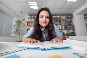 Young woman sitting at table and working with books