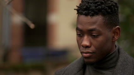 Obraz premium Contemplative young black man in meditative expression outside, close-up face
