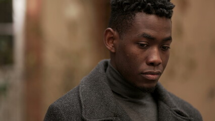 Contemplative young black man in meditative expression outside, close-up face