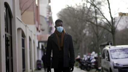 Elegant African man walking in slow-motion wearing face mask prevention against pandemic