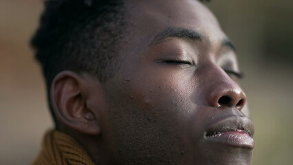 Obraz na płótnie Canvas Contemplative young black man closing eyes in meditation