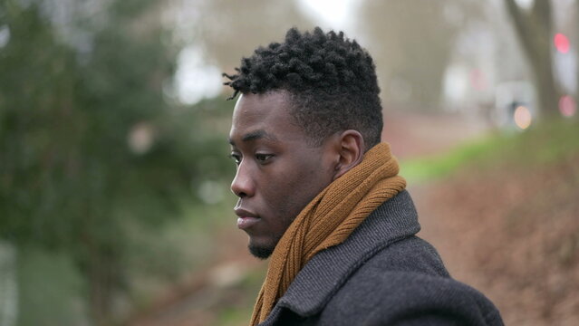 Contemplative young black man standing outside in nature park