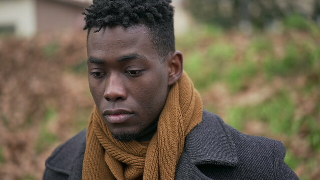 Contemplative young black man standing outside in nature park