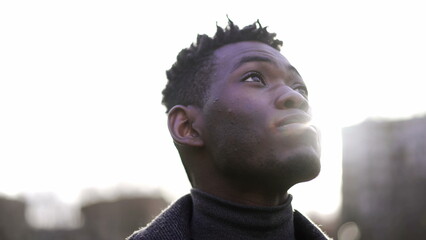 Contemplative young African black man standing looking at sky with HOPE and FAITH