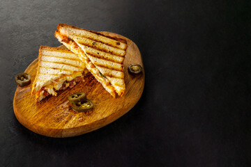 White bread club sandwich with jalapeno on wooden board.
