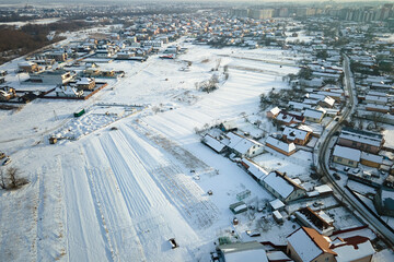 Fototapeta na wymiar Aerial view of residential houses with snow covered roofops in suburban rural town area in winter