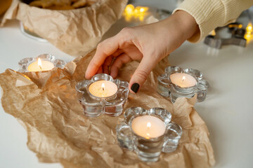 The hand puts a glass candlestick with a candle on the table