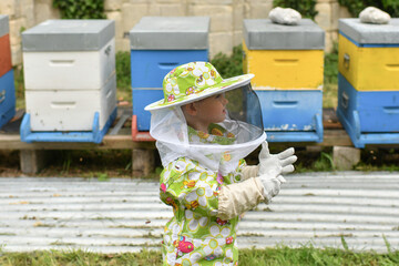 Beekeeper child in apiary in a protective suit