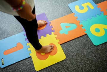 Child on a colorful hopscotch mat during treatment for flat feet