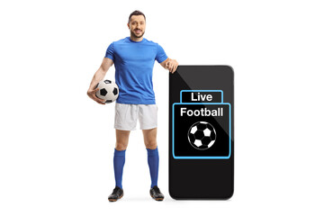 Full length portrait of a football player standing next to a big smartphone with text on screen...