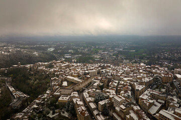 Aerial winter landscape of dense historic center of Thiers town in Puy-de-Dome department, Auvergne-Rhone-Alpes region in France. Rooftops of old buildings and narrow streets at snowfall