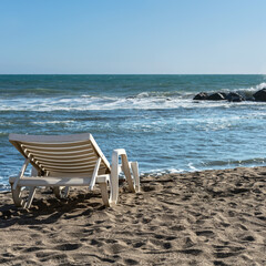 Fototapeta na wymiar plastic sun lounger on the deserted sandy beach of the Greek resort town of Lido Ostia