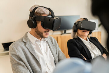 Businessman and businesswoman working with virtual reality headset. Focus on gray hair man