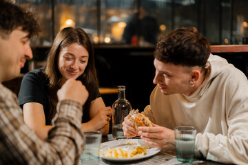 a group of friends chatting at a table in a restaurant, eating a burger and french fries