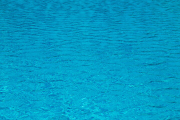 Blue water with ripples and sunny reflections in swimming pool