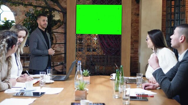 Young businessman speak at a meeting and shows a presentation in the conference room, TV with a green screen, chroma key