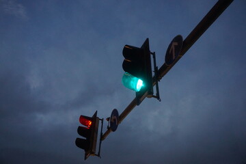 Rote und grüne Ampel mit runden blau-weißen Richtungspfeilschildern in der Luft in Stadt vor...