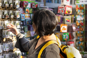 Latin woman on vacation choosing souvenirs on the Rambla in Barcelona (Spain), travel concept.