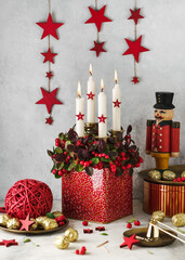 Atmospheric Christmas floral decoration. Red checkerberry plant with four white burning candles and...