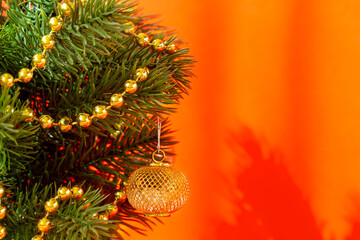 Artificial Christmas tree with decorations on a red background in the sunlight