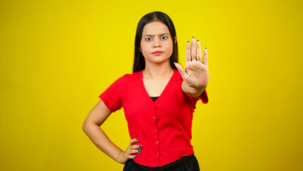 Portrait of a Asian beautiful young woman unhappy or confident standing say no, studio shot isolated yellow background, Indian female pose saying reject gesture with copy space