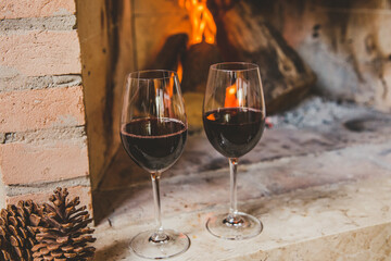 Taças de vinho tinto em lareira no inverno com pinhas