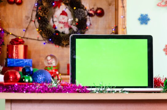 Close-up photo of green screen of laptop standing on festive table at wonderful Christmas Day. Empty space and place for text concept